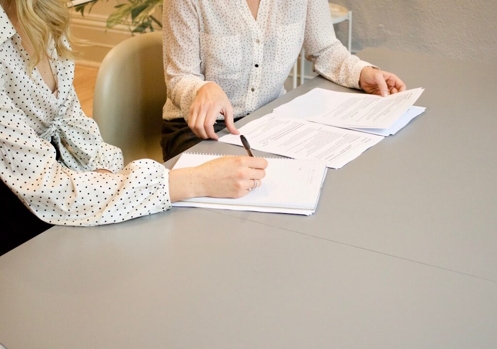 Profesionales revisando y firmando documentos durante una asesoría, imagen ilustrativa