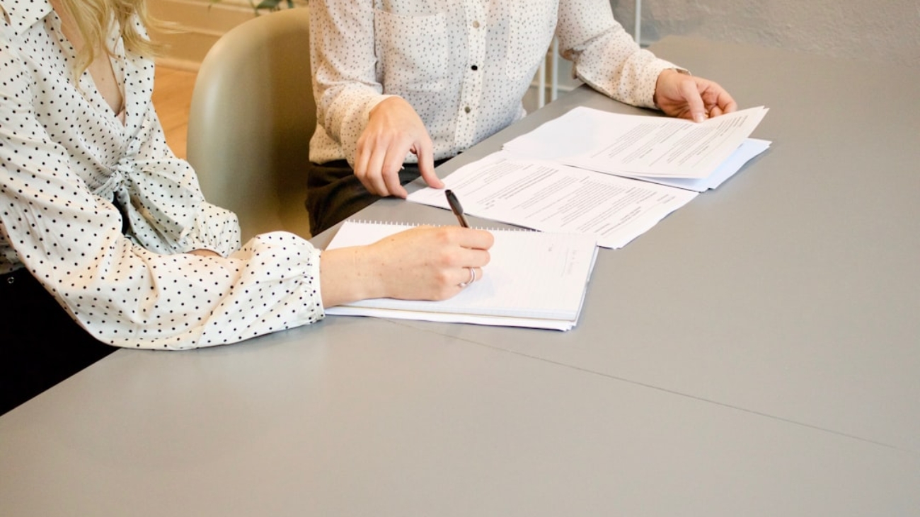 Profesionales revisando y firmando documentos durante una asesoría, imagen ilustrativa
